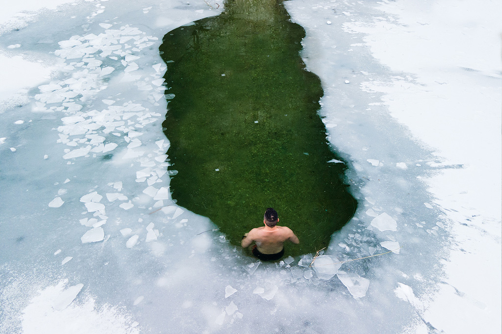 Een man zwemt in een wak in natuurijs.