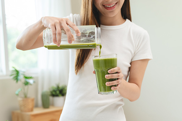 Een jonge vrouw schenkt een smoothie in.