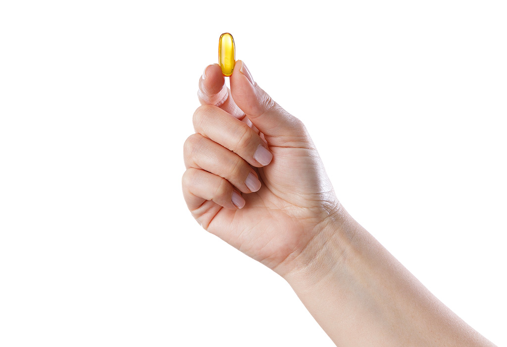 Een capsule met vis- of algenolie voor extra omega 3 in een hand.